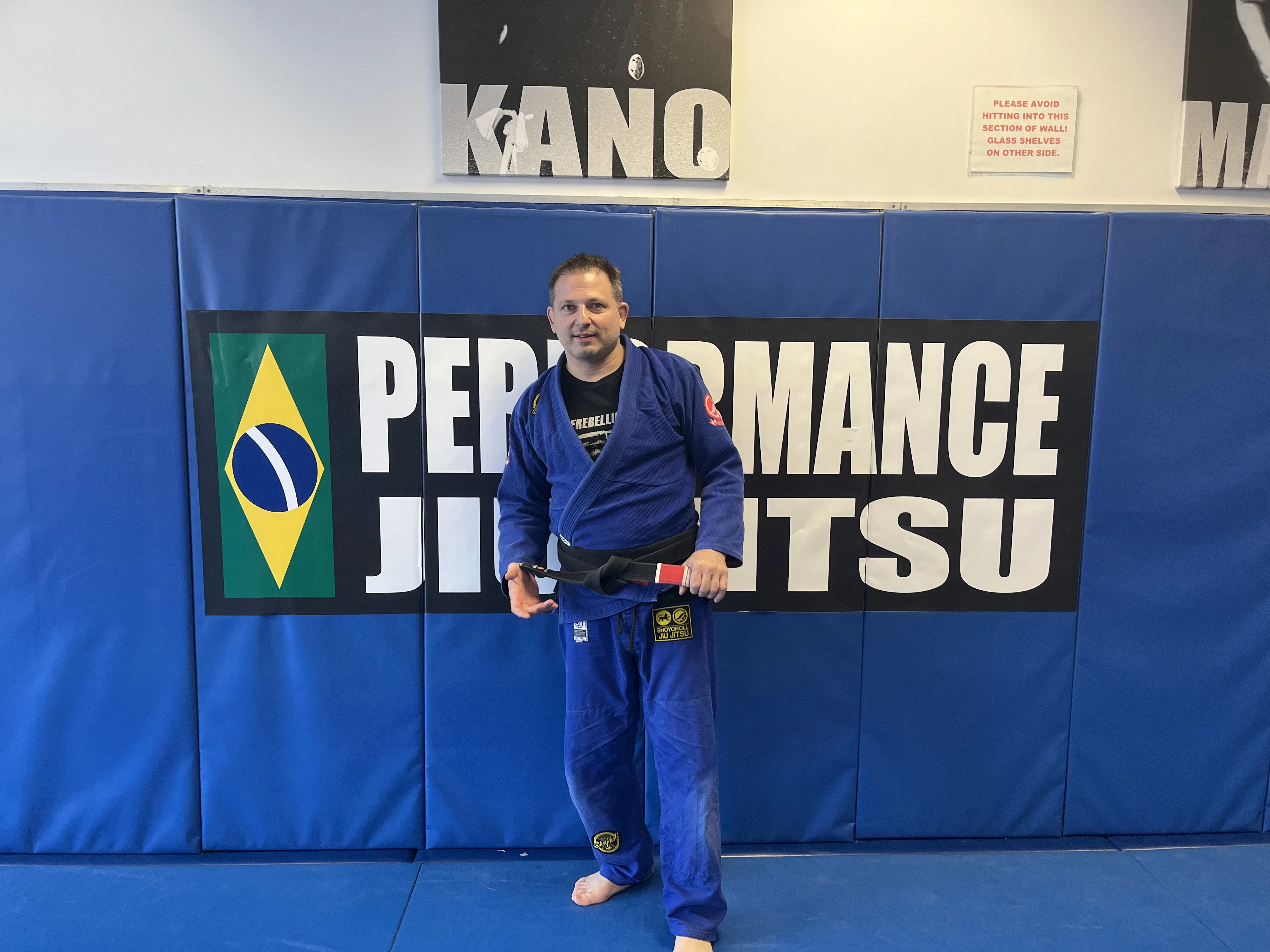 Performance Jiu-Jitsu head instructor by the academy wall banner in Fair Lawn, NJ